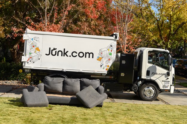 A junk truck from Junk.com sits beside an old couch better suited to junk removal than the city's local bulk trash pickup.